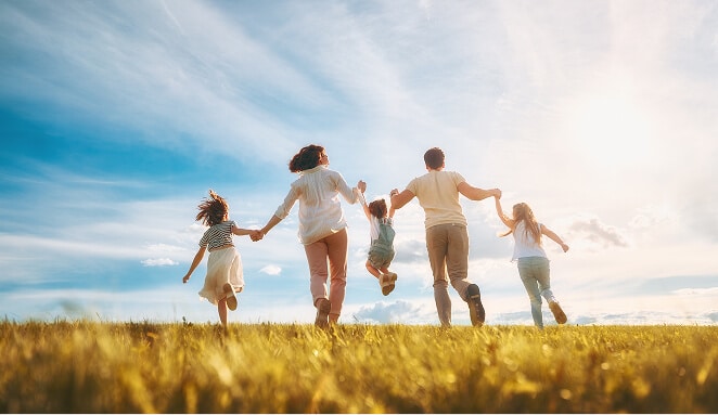 Family with three children running together through a sunny field