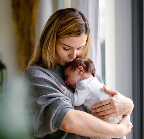 Mother holding and kissing her newborn baby