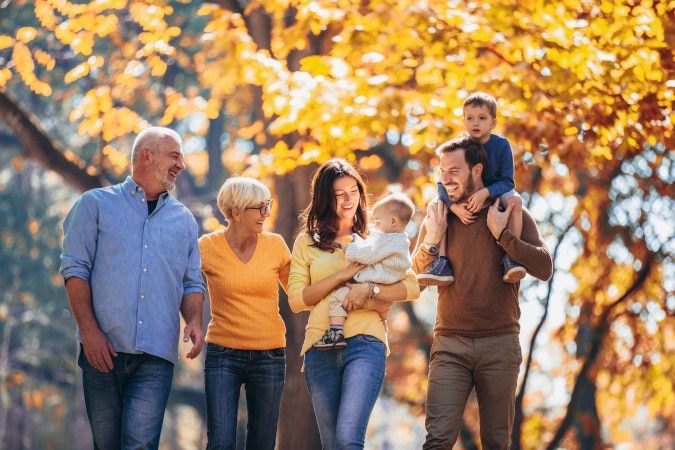 Multi-generational family walking together outdoors in autumn