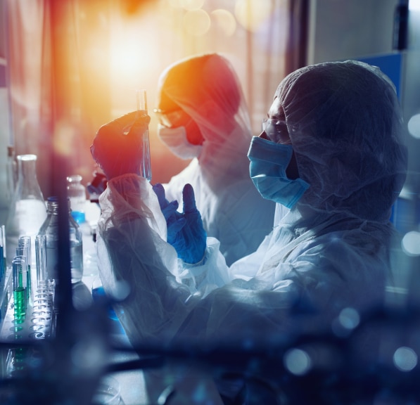 Scientists in protective clothing examining test tubes in a laboratory